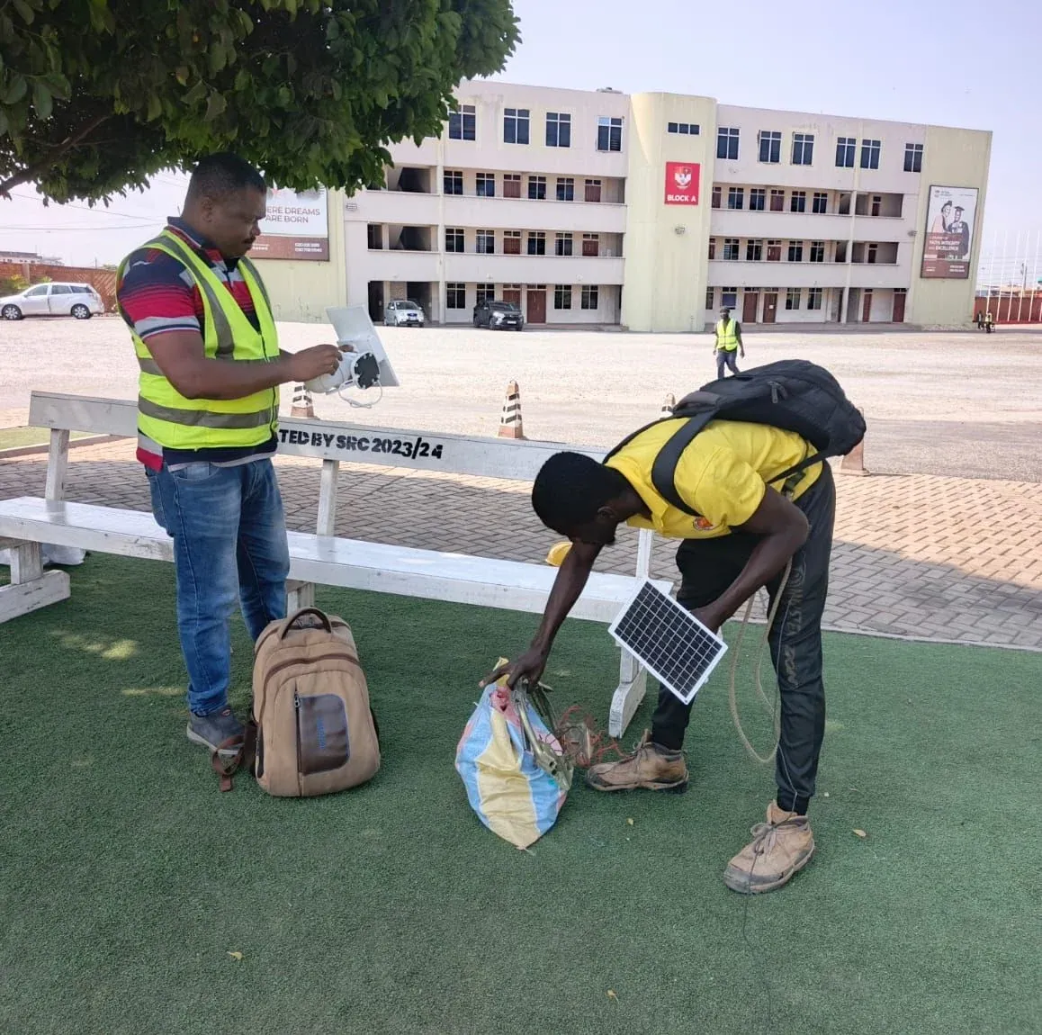 Engineers unpacking a small solar panel for a field installation on a campus