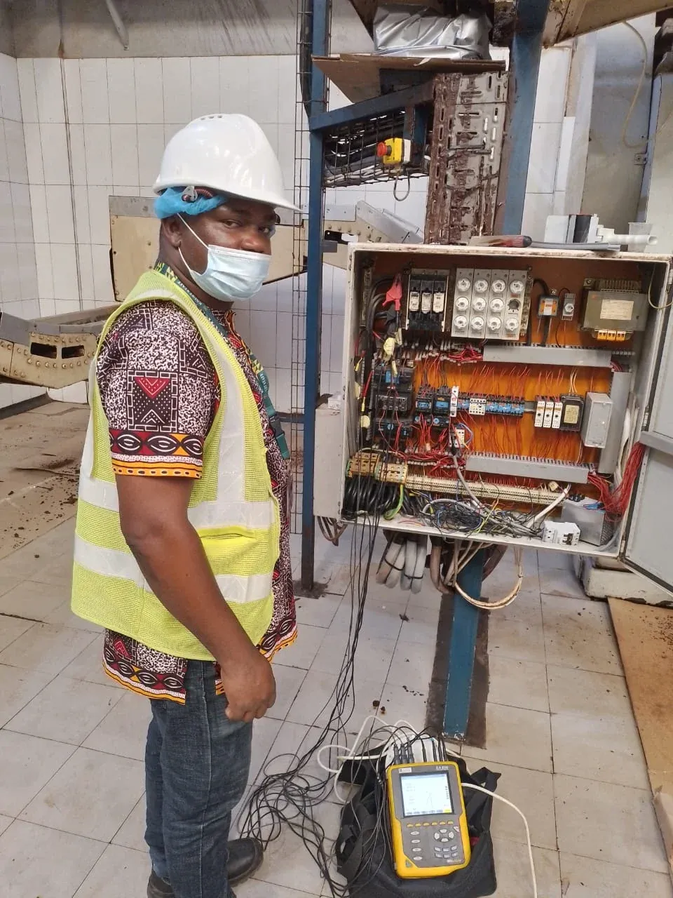 Engineer assessing an industrial control panel with test equipment connected