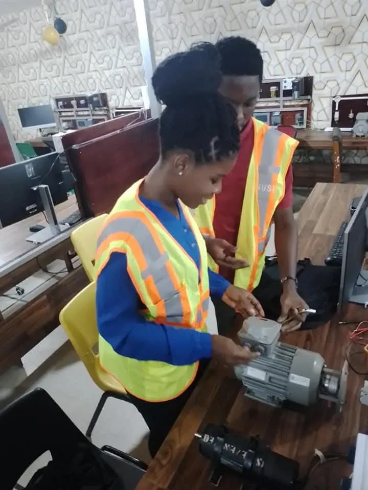 Trainee in a hi-vis vest inspecting an electric motor in the training lab